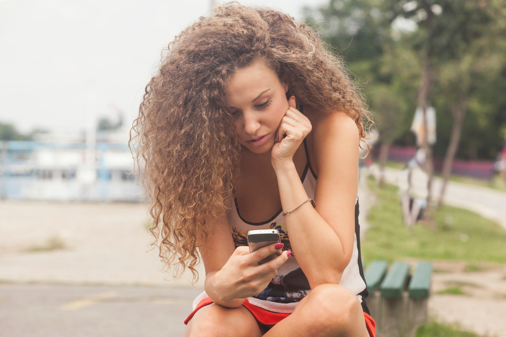 Adolescente enviando mensajes de texto por teléfono