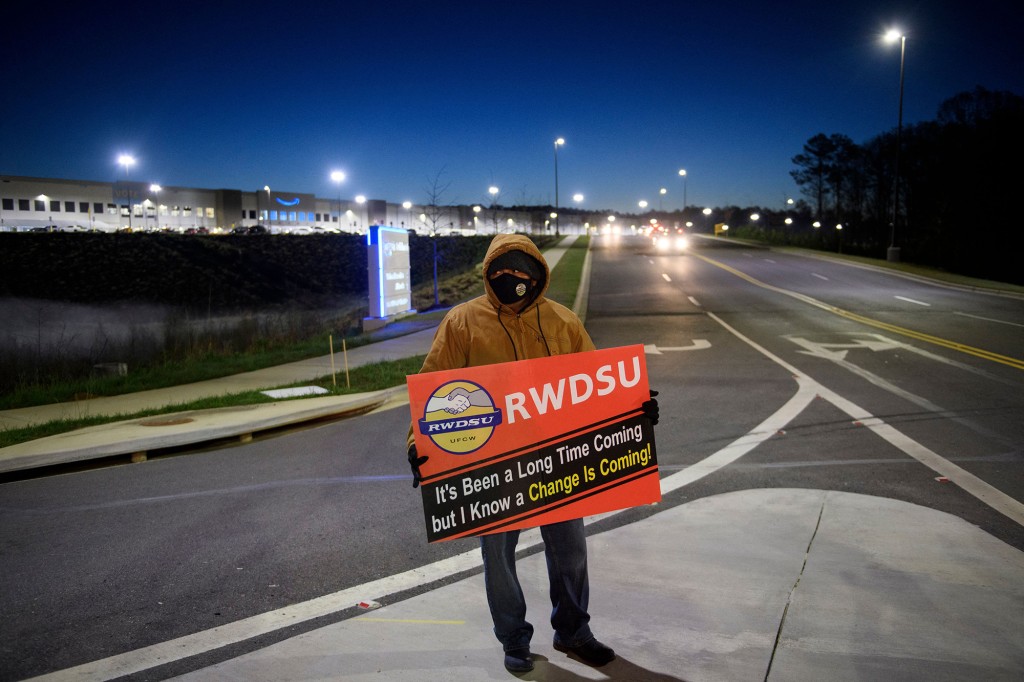 Una persona sostiene un cartel en apoyo de la sindicalización antes del amanecer fuera del centro logístico de Amazon en Bessemer, Alabama