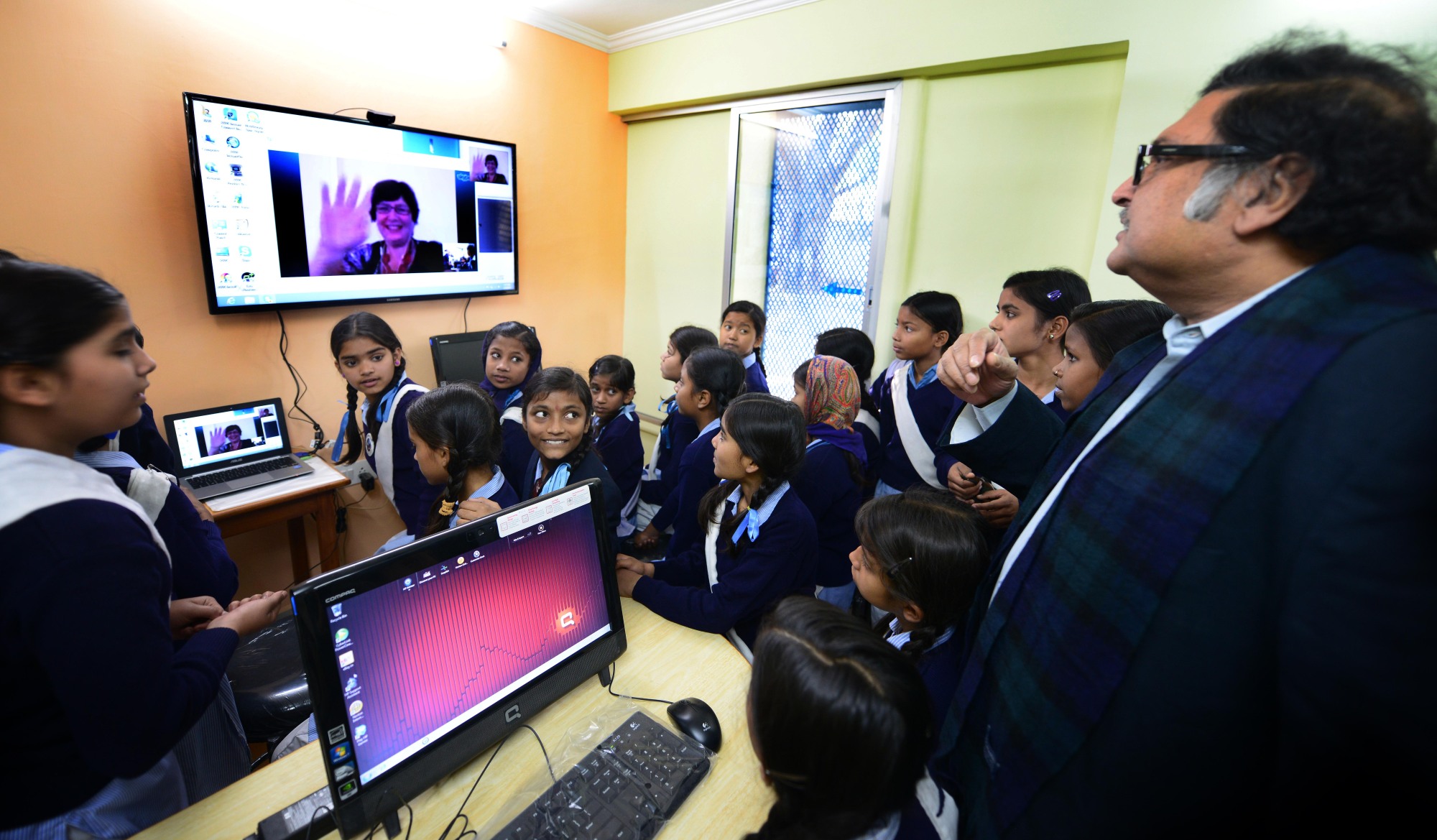 Sugata Mitra, standing at right, visits his "School in the Cloud" in New Delhi in 2014. On screen, a member of the "granny net" is the only adult supervision.