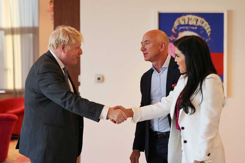 El primer ministro británico, Boris Johnson, saluda al multimillonario empresario estadounidense Jeff Bezos y a su socia, Lauren Sánchez.