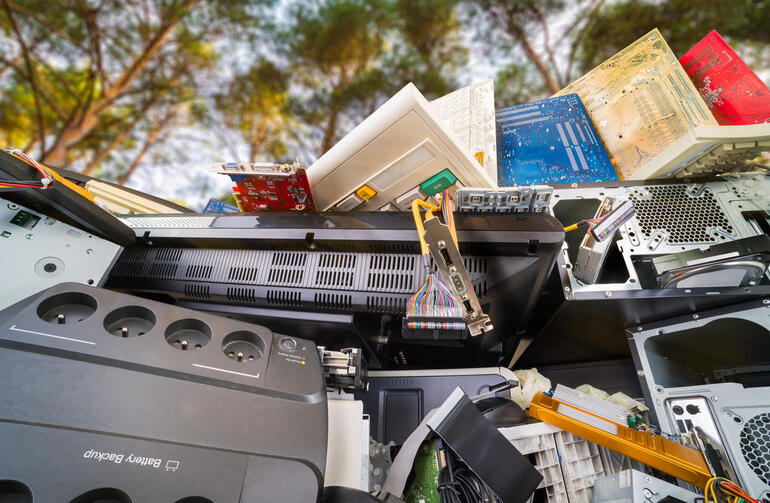 Detalle de residuos electrónicos.  Componentes de hardware informático desechados en la pila debajo de los árboles con el cielo soleado