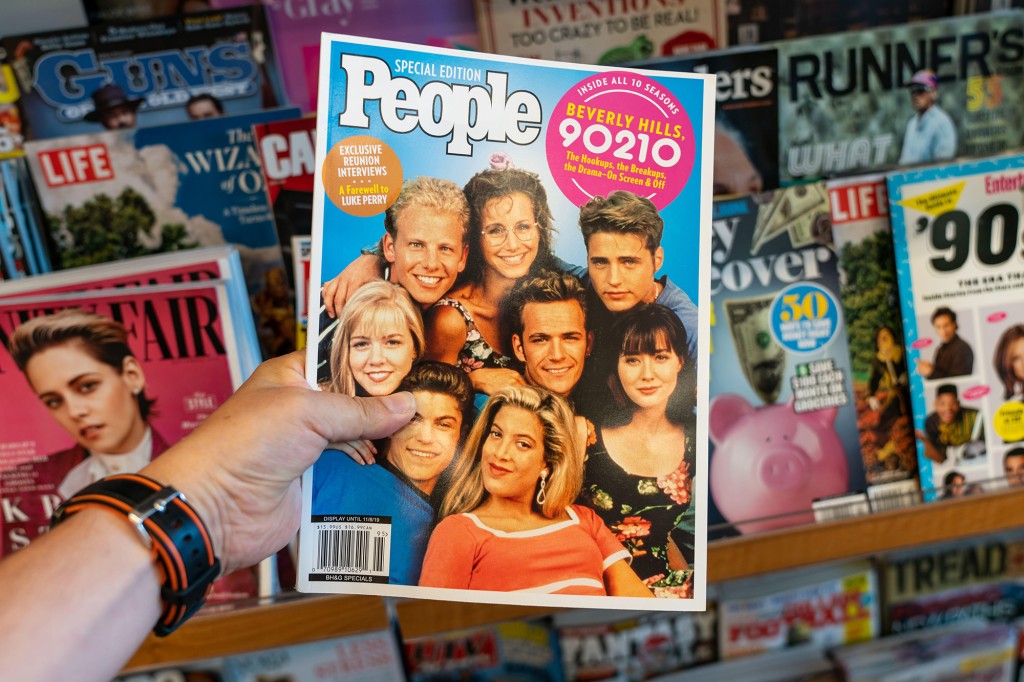   Mano sosteniendo una copia de la revista People con la serie de televisión Beverly Hills 9010 en la portada