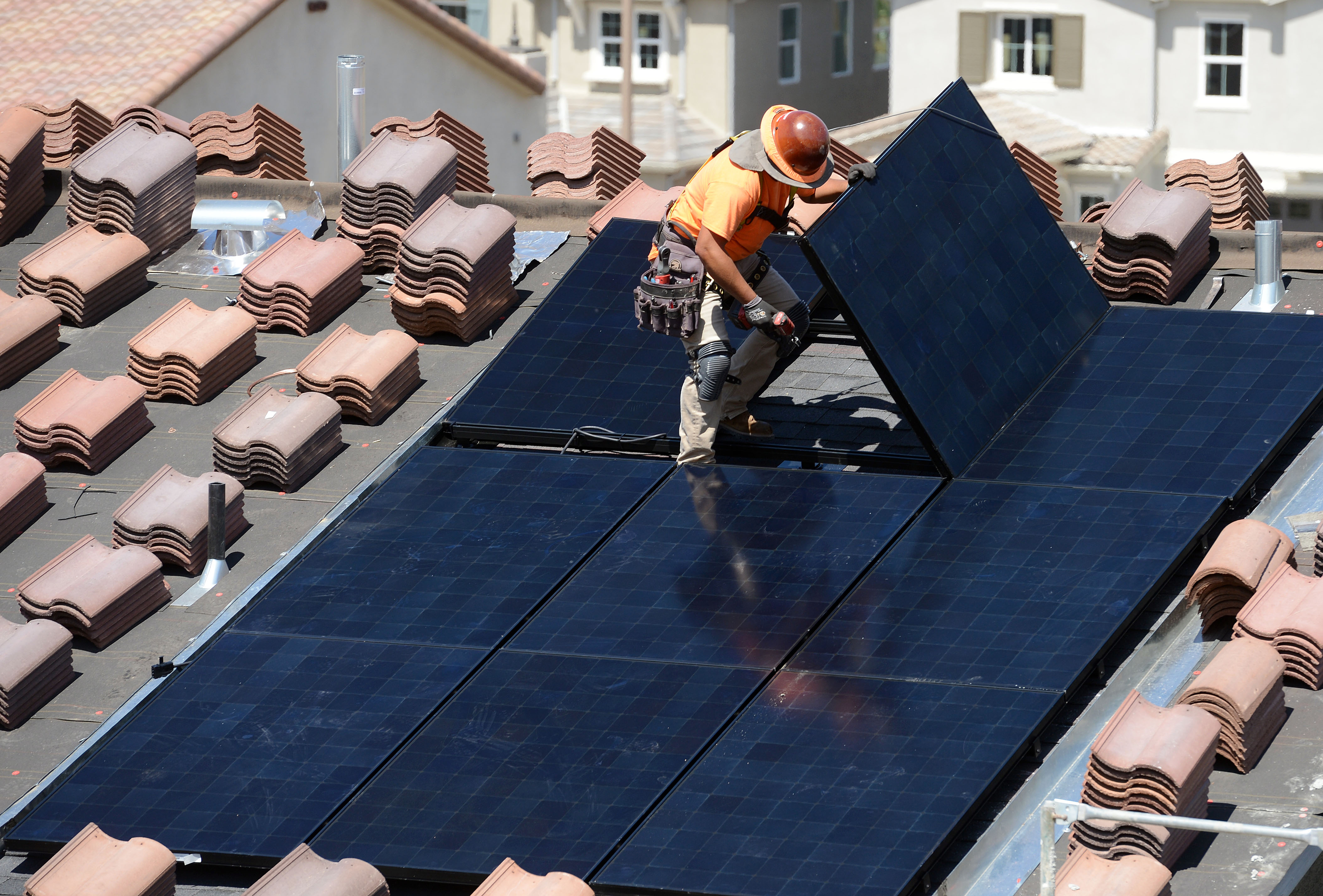Los trabajadores instalan paneles solares en los techos de las casas en construcción en California.