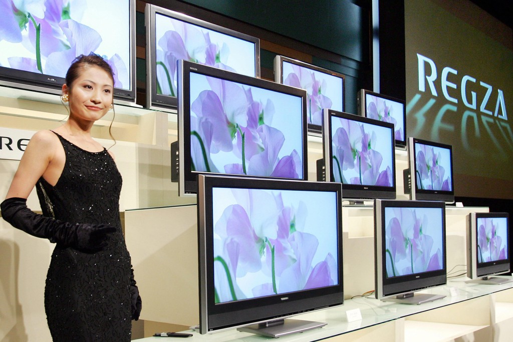 Una mujer se encuentra cerca de una pantalla de monitores de TV de pantalla plana Toshiba