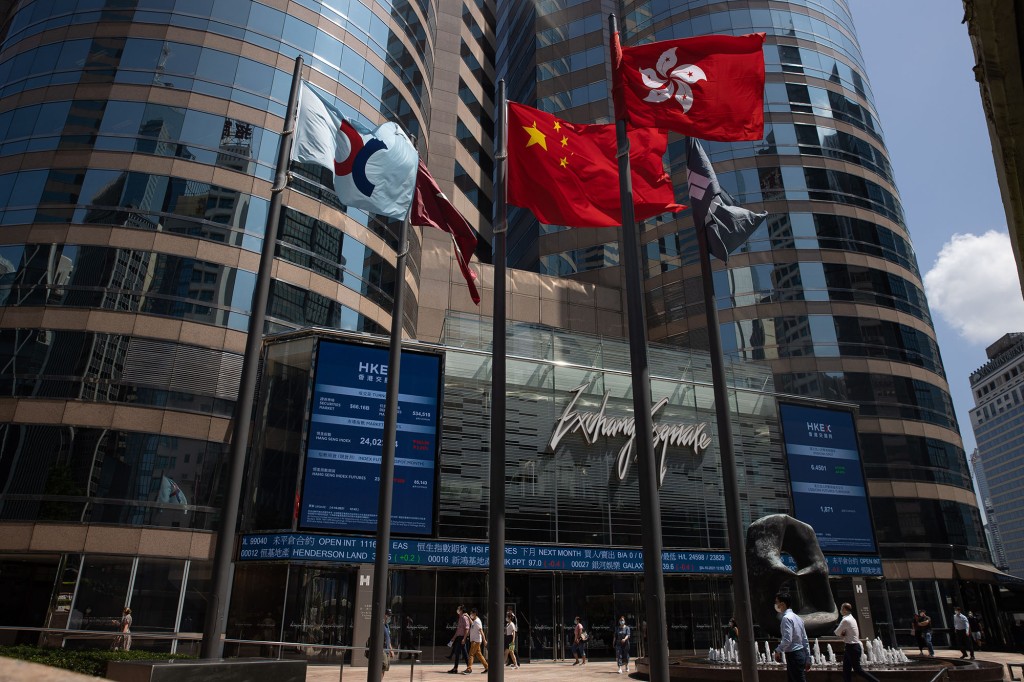Los peatones pasan junto a un indicador bursátil frente a Exchange Square, el edificio que alberga la Bolsa de Valores de Hong Kong.