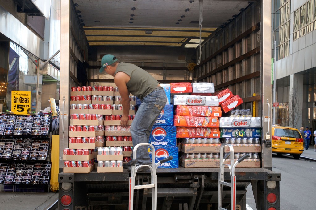 Un trabajador descarga un camión lleno de refrescos embotellados.