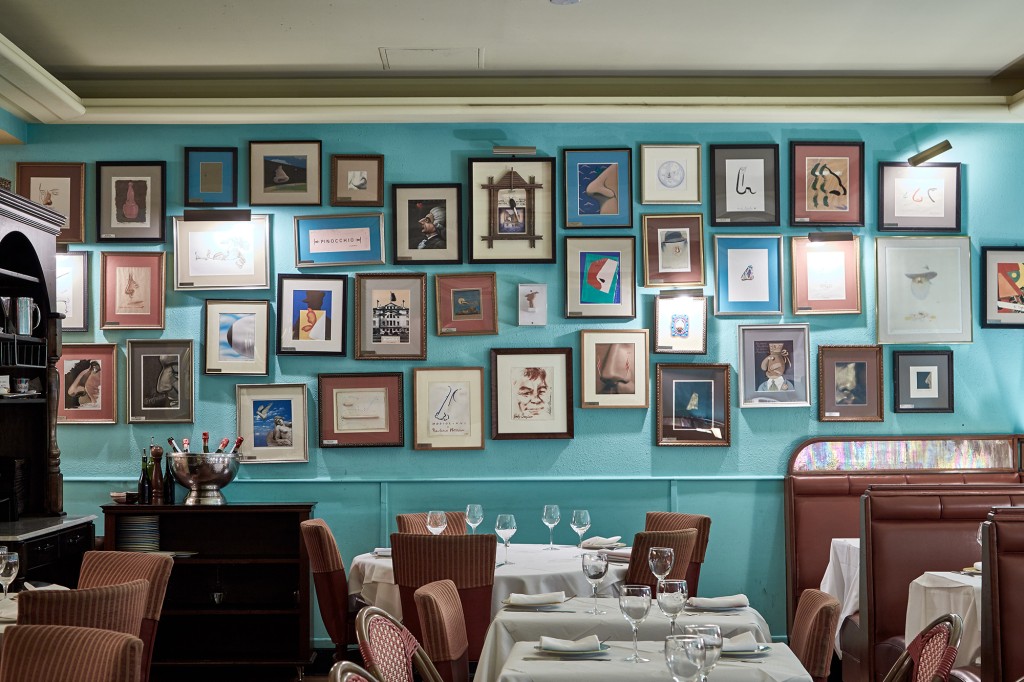 Interior de la Trattoria dell'Arte con una variedad de fotos enmarcadas en la pared y mesas para cenar