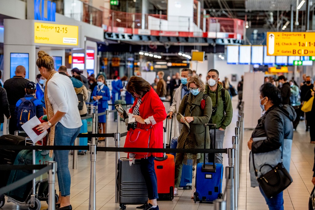 Los viajeros aéreos de pie en línea dentro de una terminal de aeropuerto