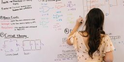 una mujer escribiendo problemas de matemáticas en una pizarra