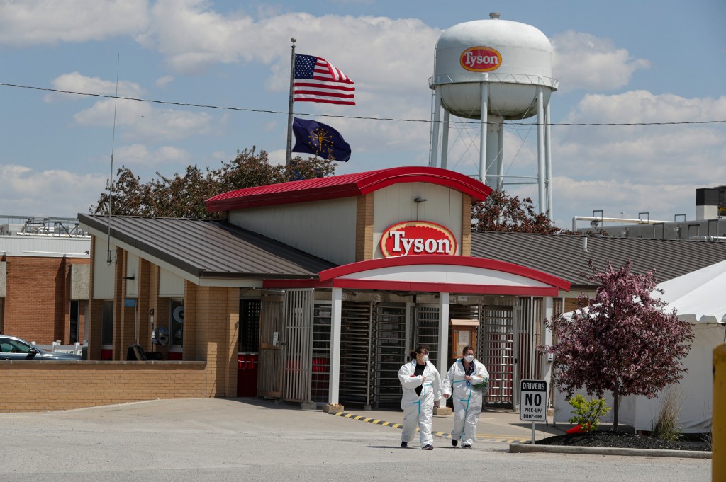 Dos empleados de Tyson Foods salen de la planta con trajes protectores blancos.