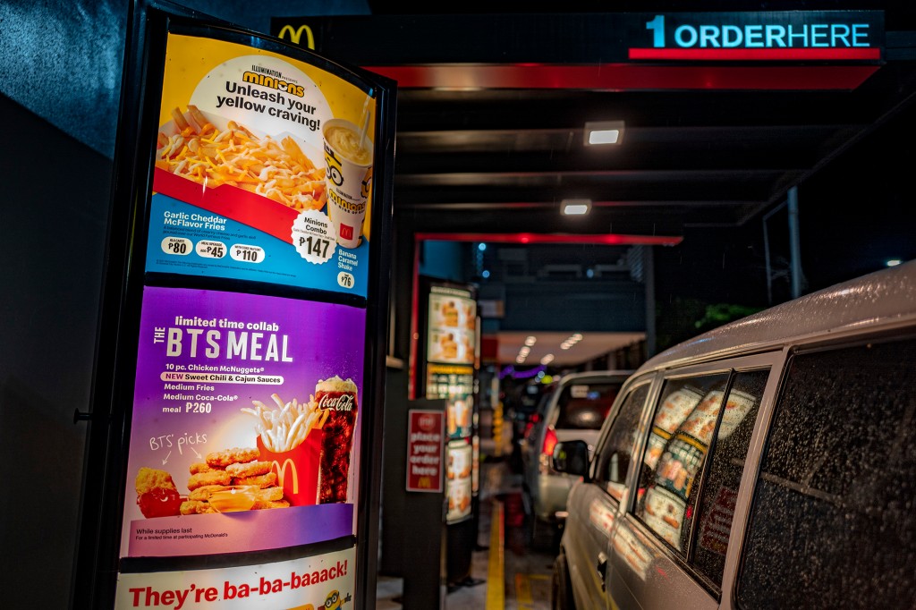 Un automóvil está al lado de un tablero de menú de drive-thru.