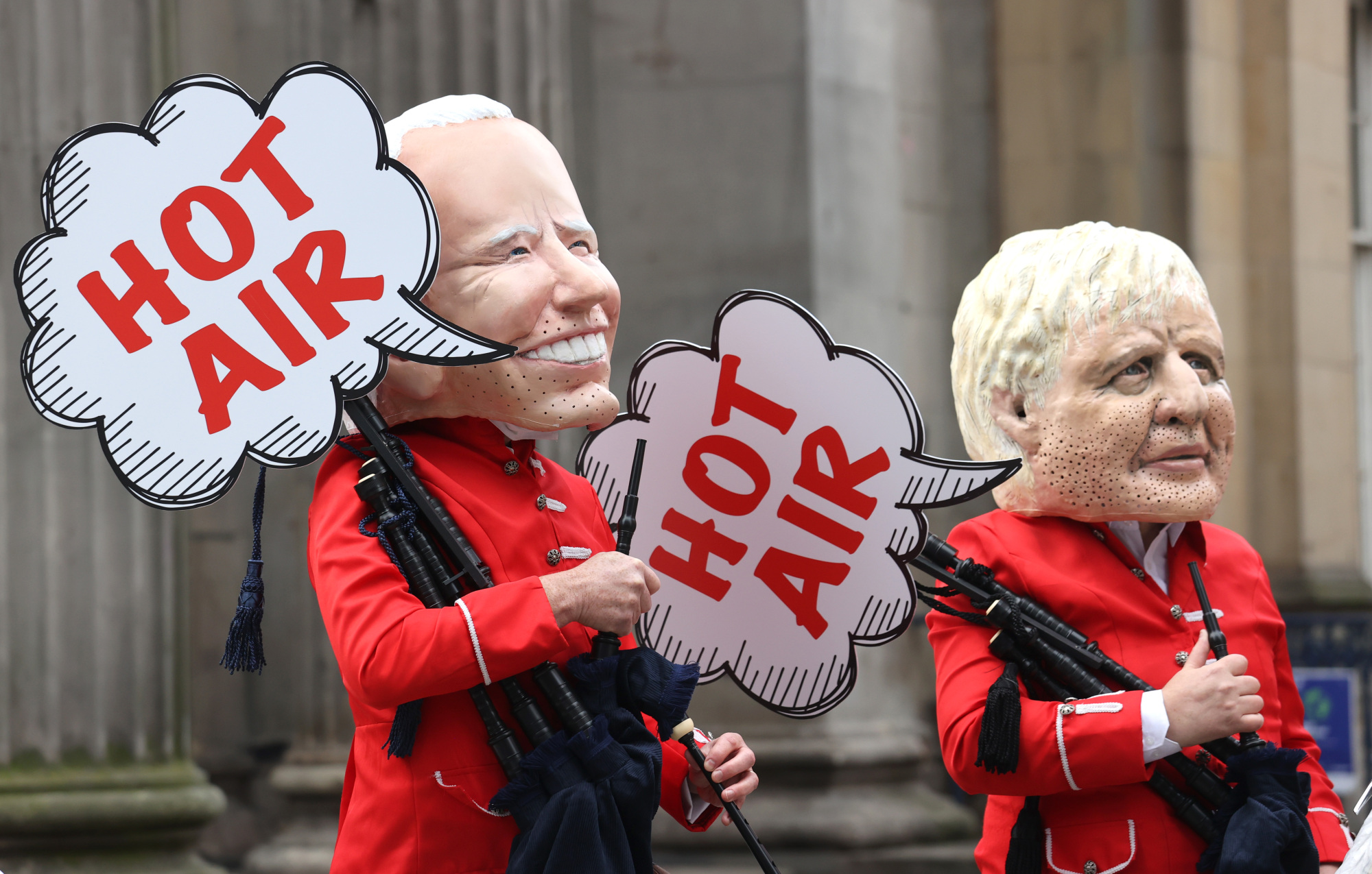 Los manifestantes de Oxfam se disfrazan del presidente estadounidense Joe Biden y del primer ministro británico Boris Johnson "soplando aire caliente" fuera de la Galería de Arte Moderno de Glasgow.
