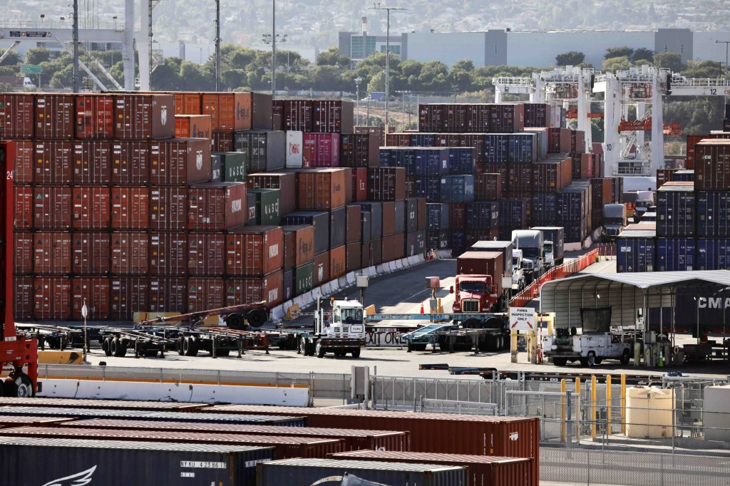 Los camiones son vistos por los contenedores apilados en el puerto de Los Ángeles, California.