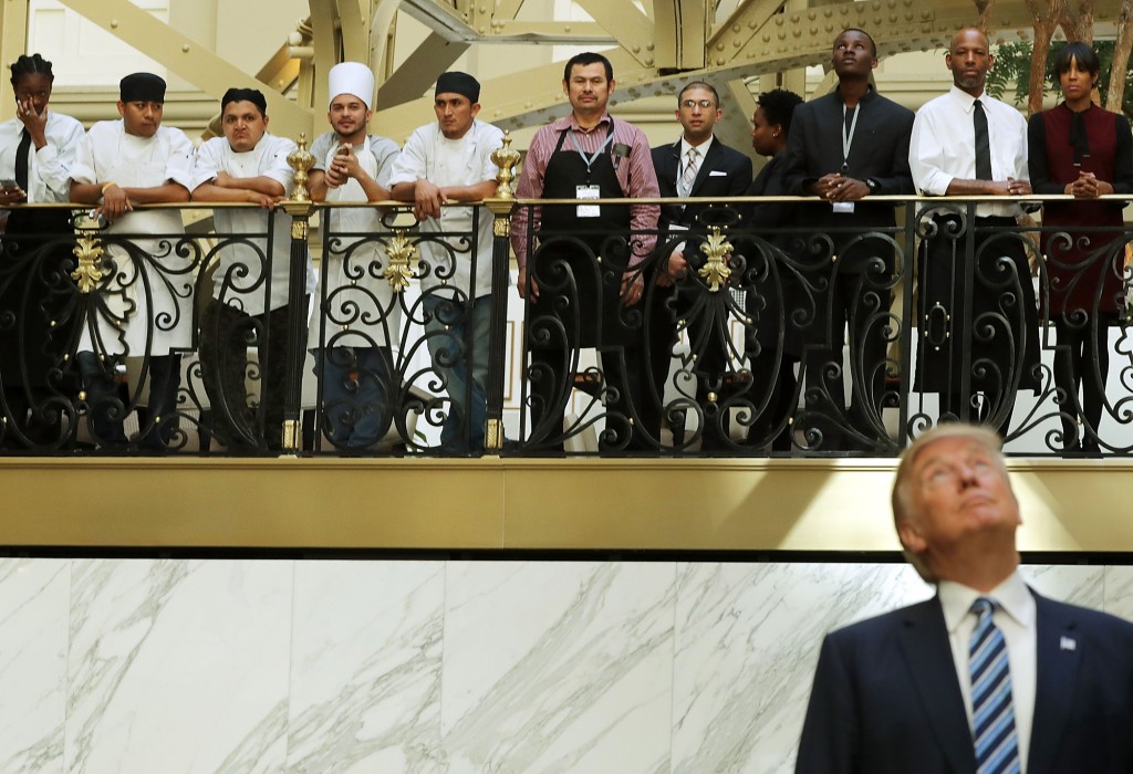 Donald Trump mira hacia arriba mientras los empleados del hotel observan.