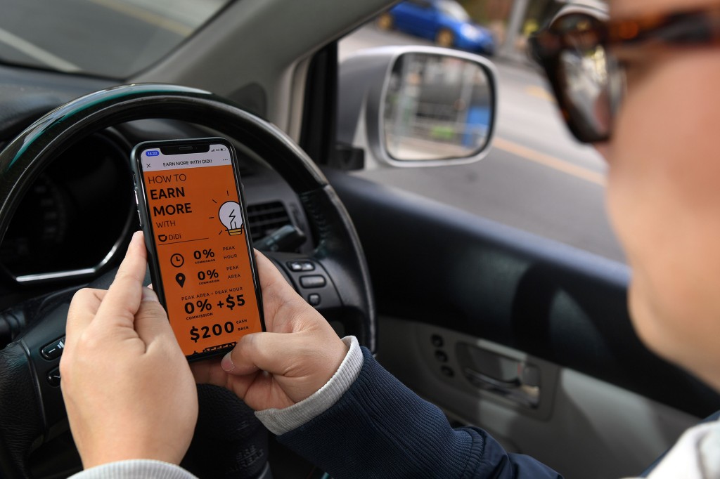 Un conductor de Didi que usa la aplicación Didi en su teléfono inteligente detrás del volante de su automóvil.