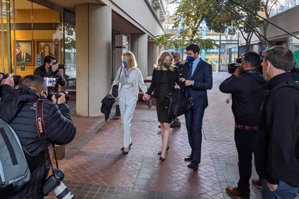 Elizabeth Holmes, en el centro, ingresa al edificio federal Robert F. Peckham con su socio, Billy Evans, a la derecha, y su madre, Noel Holmes, en San José, California, el martes 7 de diciembre de 2021. Mirando en el extremo derecho es John Carreyrou, el ex reportero del Wall Street Journal que escribió la historia de octubre de 2015 que expuso fallas en la tecnología de análisis de sangre de Theranos. 