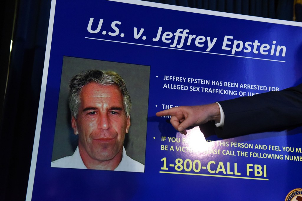 Foto de Jeffrey Epstein en una pantalla gigante con la etiqueta US v. Jeffrey Epstein mientras los fiscales anuncian los cargos en su contra