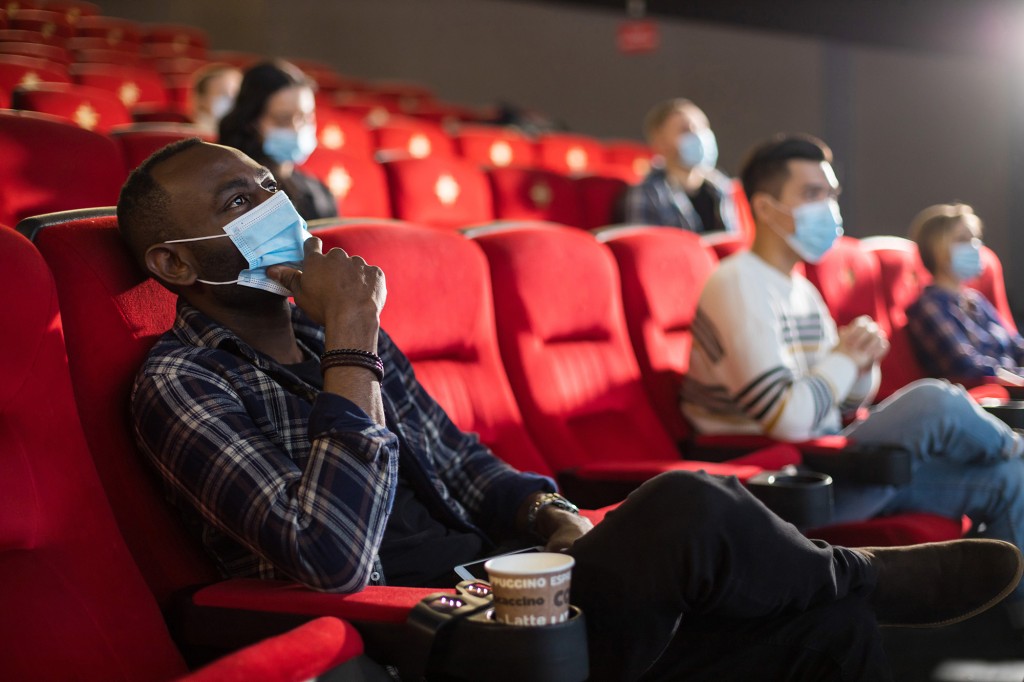 La gente se sienta en la sala de cine y ve una película con máscaras médicas y mantiene la distancia.  Covid-19 y la industria del cine