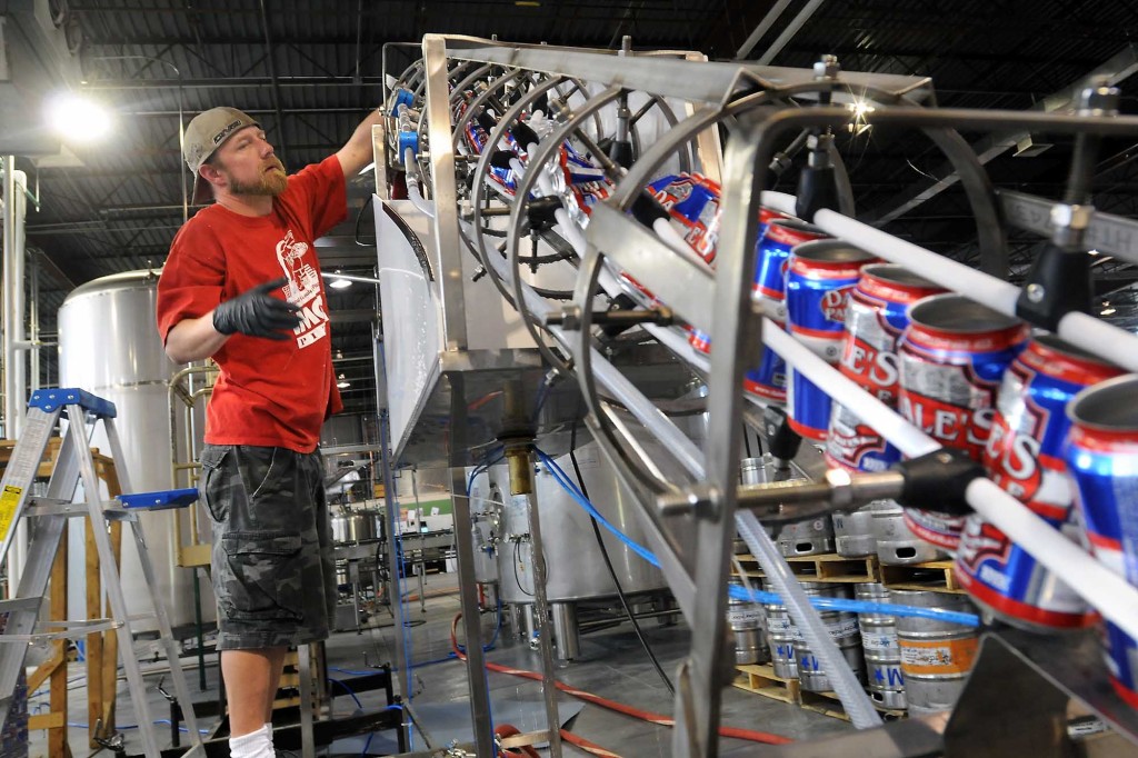 Un hombre que trabaja en una planta de conservas de Oskar Blues con latas en una cinta transportadora