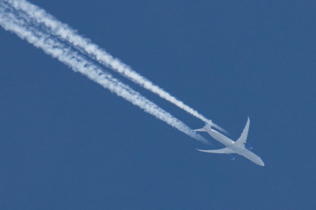 Un avión Boeing 787 Dreamliner de United Airlines sobrevuela el cielo azul de Ámsterdam.