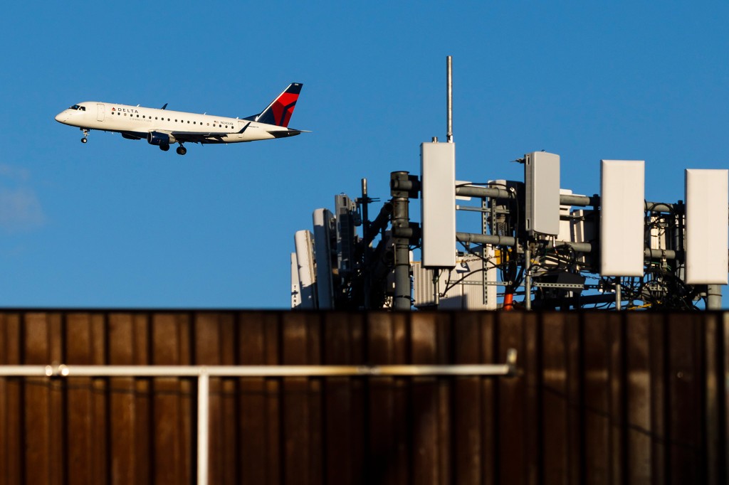 Un avión de Delta Airlines que se aproxima para aterrizar en el aeropuerto LaGuardia pasa por antenas de telecomunicaciones en una azotea en Queens.