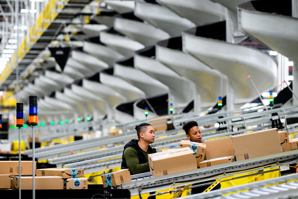 Los hombres trabajan en la cinta transportadora dentro de la estación de distribución de Amazon en Staten Island