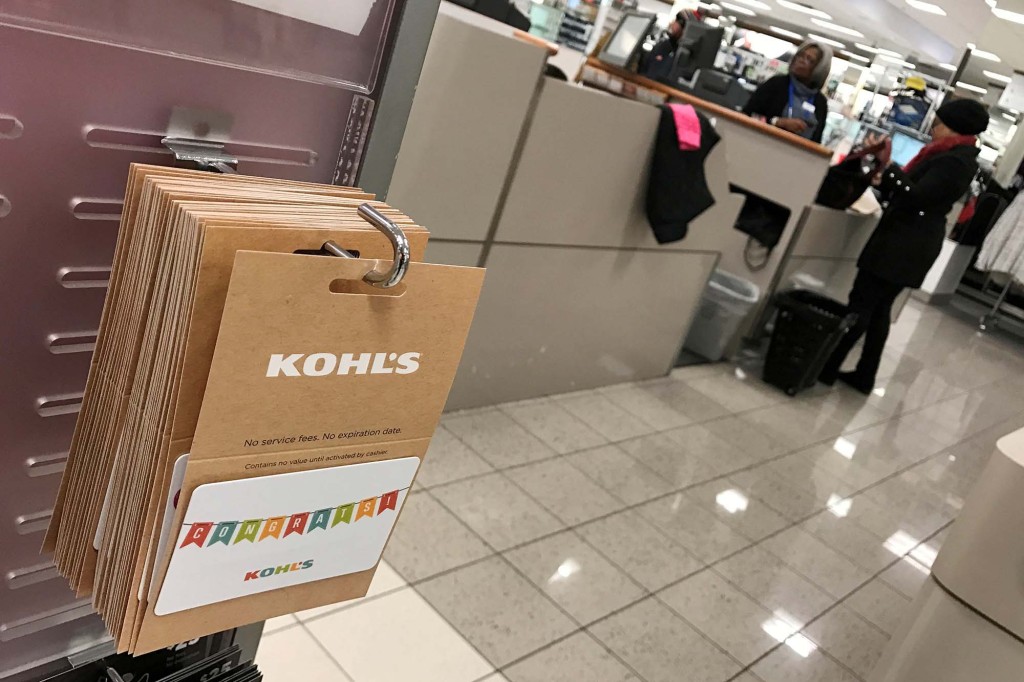 Tarjetas de regalo de Kohl's vistas dentro de un Kohl's con un comprador y un vendedor al fondo