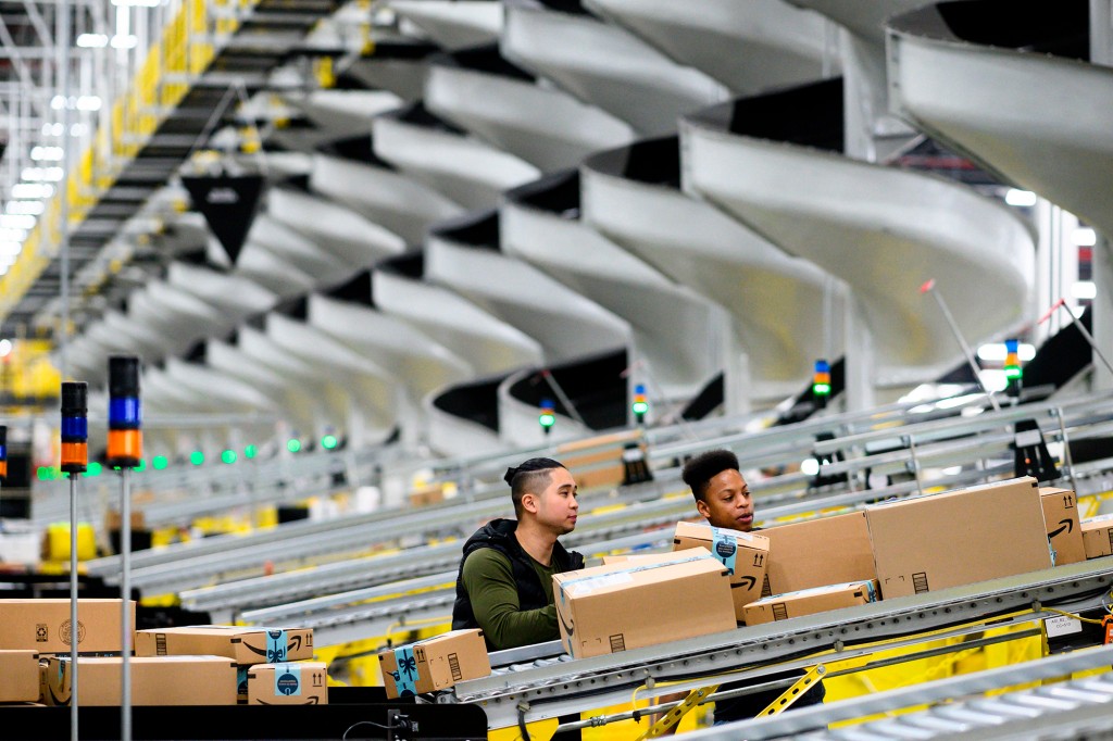 Hombres que trabajan con paquetes en una cinta transportadora en una instalación de Amazon en Staten Island, NY