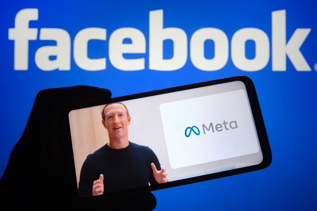 El CEO de Meta, Mark Zuckerberg, visto en la pantalla de un teléfono inteligente junto a un logotipo de Meta con un logotipo de Facebook en el fondo en una ilustración fotográfica