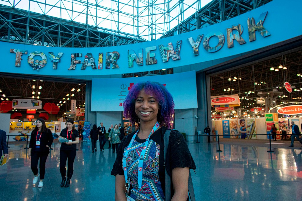 Un asistente de pie frente a la pancarta de Toy Fair dentro del Javits Center.