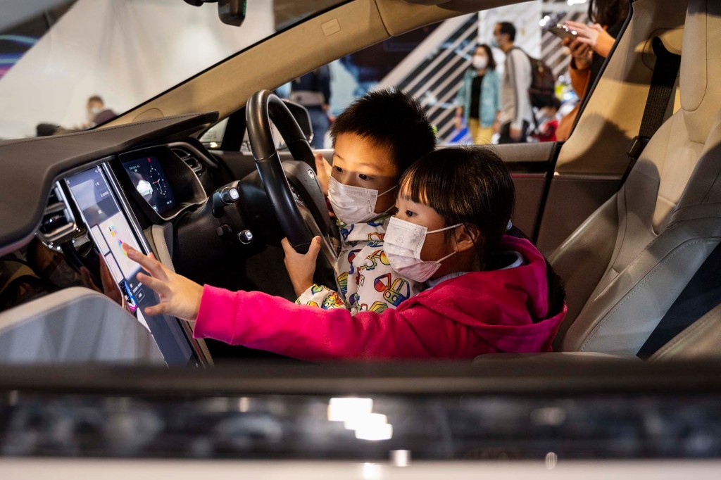 Dos niños prueban y se sientan en un Tesla Model X en una exhibición de autos